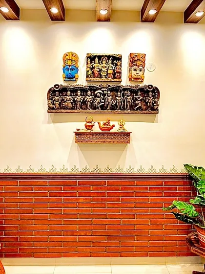 A wall decorated with traditional art, including carved masks and panels, set against a brick-textured lower wall.