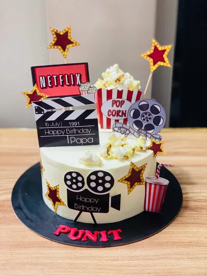 A fun movie-themed cake with popcorn, a film reel, and a Netflix logo.