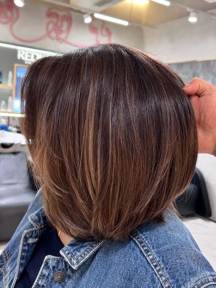 A side view of this beautiful brown bob with highlights. The color adds depth and interest to the classic cut.
