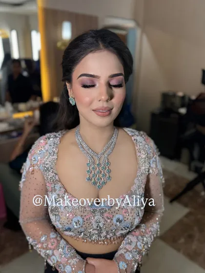 The soft pink tones in the makeup perfectly complement the floral embroidery on her blouse.
