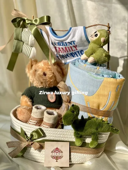 This hamper is for the 'Current Family Favorite'. It includes a cool teddy bear, dinosaur toys, and a cozy blanket, all in a handsome green and brown color scheme.