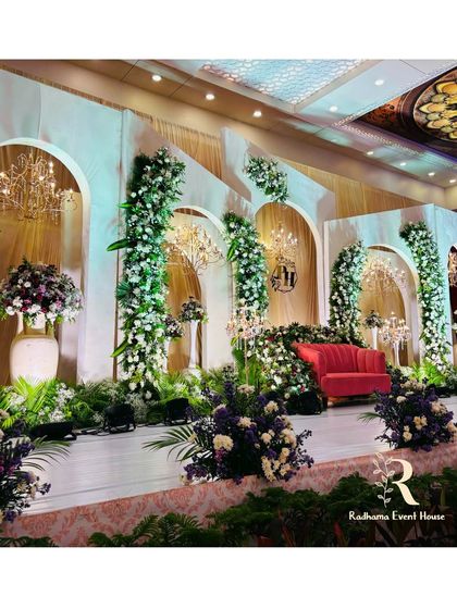 A wide shot of the elegant white arched stage, showing how the floral arrangements and chandeliers come together to create a grand, cohesive look. The design feels both modern and timeless.