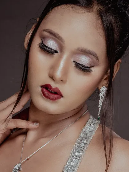 A close-up beauty shot focusing on the model's shimmering eyeshadow and perfectly applied makeup. The soft lighting creates a glamorous and dreamy mood.