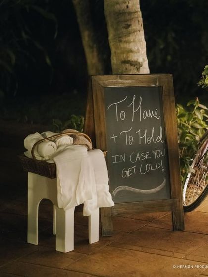 A thoughtful detail for a cool evening: a basket of blankets for guests with a charming sign that reads 'To Have + To Hold in case you get cold!'
