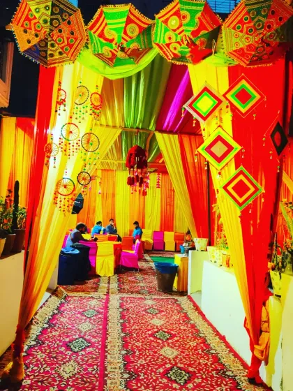 A tent entrance at night, glowing with warm lights and vibrant colours, creating an inviting atmosphere for an evening event.