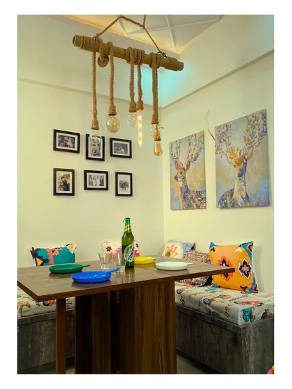 A rustic and creative dining nook featuring bench seating and a unique DIY-style rope and bulb chandelier, perfect for a casual, bohemian vibe.