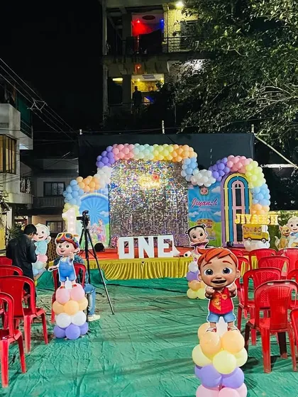 A ground-level view of the Cocomelon party setup, highlighting the character props and the path leading to the main stage.