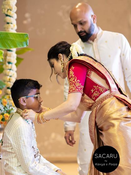 A candid moment from the ceremony, showing the intricate embroidery on the back and sleeves of Anusha's vibrant red blouse.
