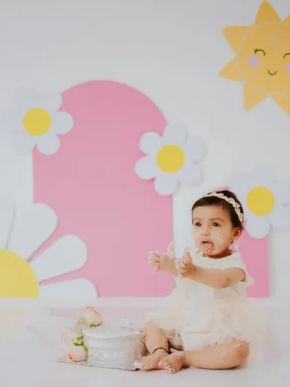 A different take on the daisy theme, this time with a soft pink background. This little girl is just getting started on her pretty white cake.