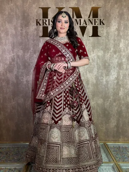 A full-length photo of the maroon velvet bridal lehenga. You can see the geometric patterns on the skirt, which makes it a very unique and modern choice.