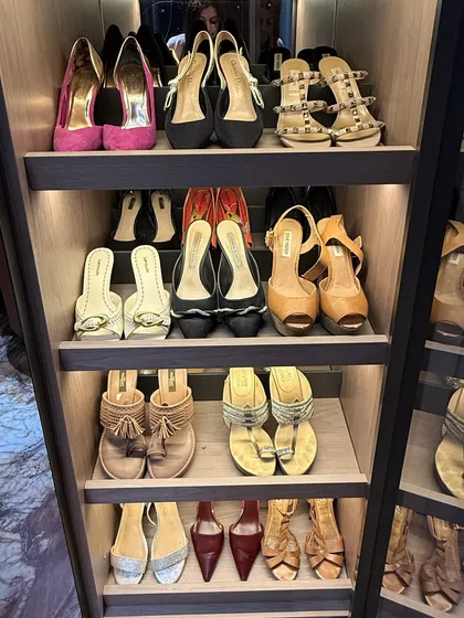 Another angle of a luxury shoe collection, showcasing a variety of heels and sandals organized on well-lit shelves.