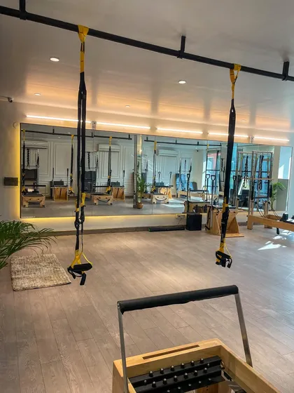 A wide-angle view of our studio, showing the large mirrors that help clients check their form and the ample space for movement. The combination of wood and white creates a modern, clean feel.