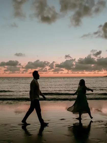 A silhouette of a couple walking along the beach at sunset, a timeless and romantic scene. This photo captures a quiet, peaceful moment of togetherness.