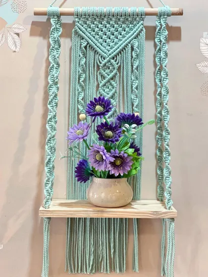 My work is both beautiful and practical. This sturdy macrame wall shelf, shown here with a lovely vase, is perfect for holding small plants, books, or your favorite decorative items.