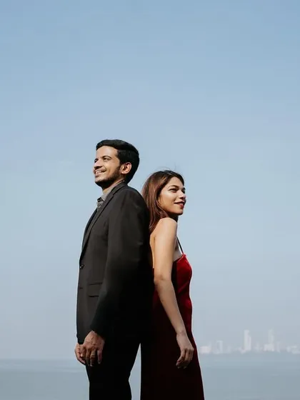 A stylish, back-to-back pose against the open sea and sky, creating a modern and powerful image of the couple as partners.