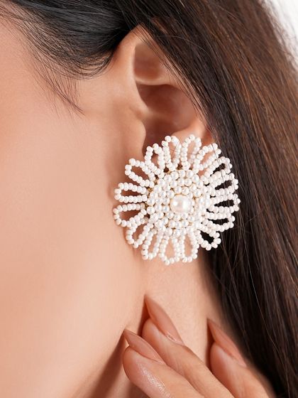 A model showcasing our classic white beaded floral studs. A timeless piece that is currently on sale.