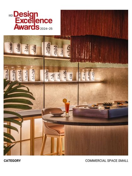 A close up of the sushi bar, showcasing the custom tassel light fixture and the warm, indirect lighting on the back-bar display. This intimate seating area offers a different, more focused dining experience.