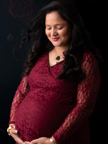 A beautiful, classic portrait focusing on the mother's serene expression. The lace detail on this red gown adds a touch of romance and texture.