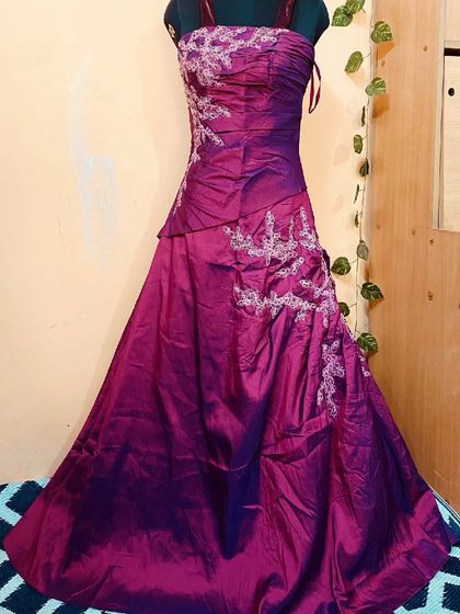 This deep purple gown features a ruched satin bodice with silver embroidery. It's an elegant and form-fitting rental choice for a formal evening event.