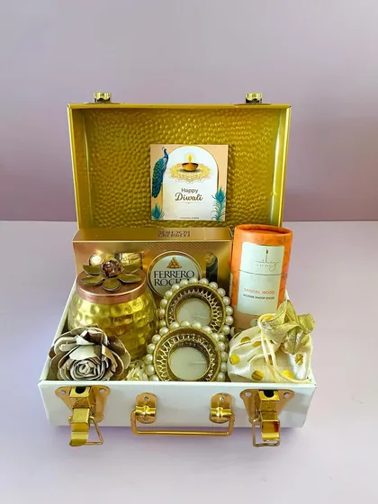 This premium metal trunk in white and gold is a showstopper. This version is curated with Ferrero Rocher, a decorative jar, pearl T-light holders, and incense.
