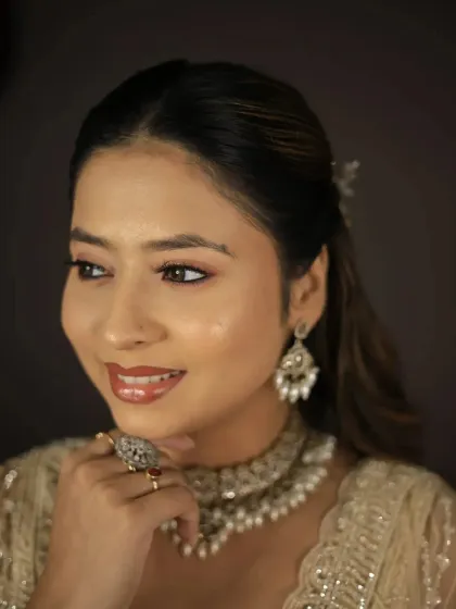 A happy close-up of a model wearing our beige lehenga and a beautiful pearl and kundan choker.