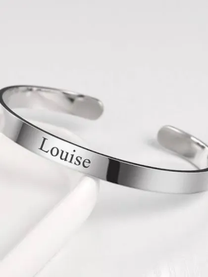 A classic silver-finish metal kada, or bracelet, with a name elegantly engraved on the surface. It's a timeless and personal piece of jewelry.