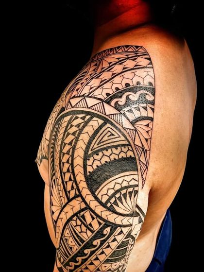 A side view of a large Polynesian tattoo. You can see how the design flows from the chest over the shoulder and down the arm.