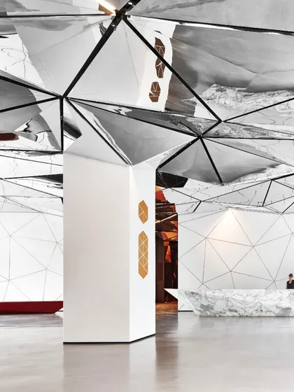 A wide view of the lobby showing the relationship between the central columns, the reception area, and the waiting spaces. The design creates distinct zones within a unified whole.