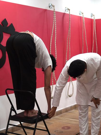 A chair can be your best friend for forward bends if you have tight hamstrings. Here, I am assisting a student in a supported Uttanasana, helping him get a deep spinal stretch without rounding his back.