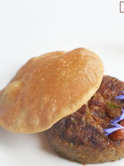 The succulent Shami Kabab paired with a fluffy Poori, a true Lucknow specialty featured in our "Zaika-e-Rooh" pop-up.