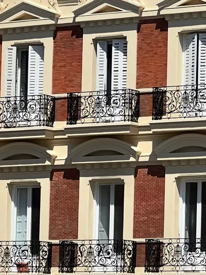 The striking contrast of red brick, white trim, and black ironwork on a building facade in Spain. The color palette and repeating architectural elements create a visually pleasing and harmonious composition that feels both stately and full of character.