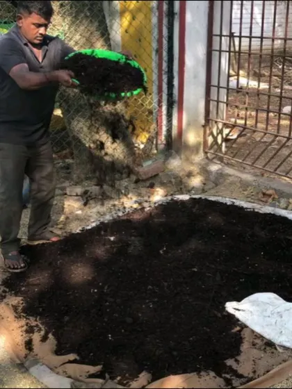 A volunteer proudly displays the finished product of a community composting effort. This dark, crumbly compost is a testament to the collective effort of residents who chose to divert their waste from landfills.