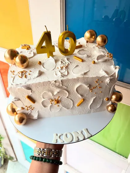 A stylish way to celebrate 40! This is a half-cake, shaped to be part of a larger number design, decorated in white and gold.