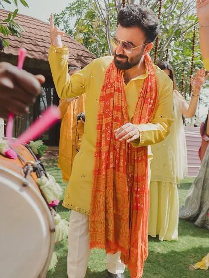 The groom enjoying the dhol beats, capturing the high-energy and traditional start to the Haldi ceremony.
