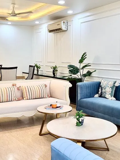 This angle showcases the full layout of the refurbished living and dining room. The mix of a classic white sofa, modern blue couches, and patterned chairs creates a dynamic yet cohesive look.