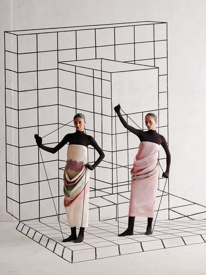 Two models interact with a 3D line installation. The styling is identical, turning the models into architectural elements themselves.