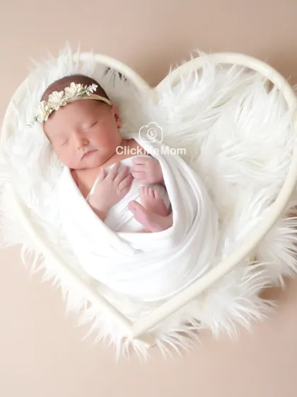 Simple, pure, and angelic. A classic portrait in all white, with your baby nestled safely in a heart-shaped basket, creates a timeless image of innocence you will cherish forever.