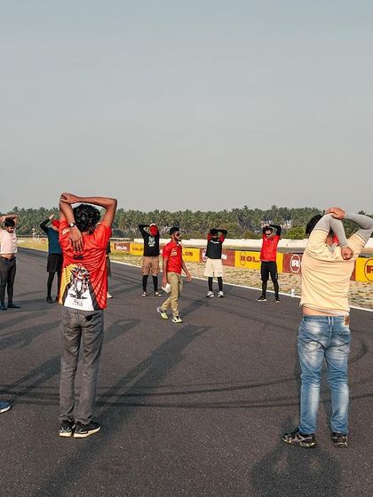 A group stretching session on the track. Proper warm-ups are essential for preventing injury and preparing the body for the physical demands of riding.