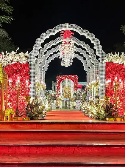 The grand entrance to the wedding venue. The layered arches, crystal chandeliers, and floral walls create a sense of grandeur and anticipation.