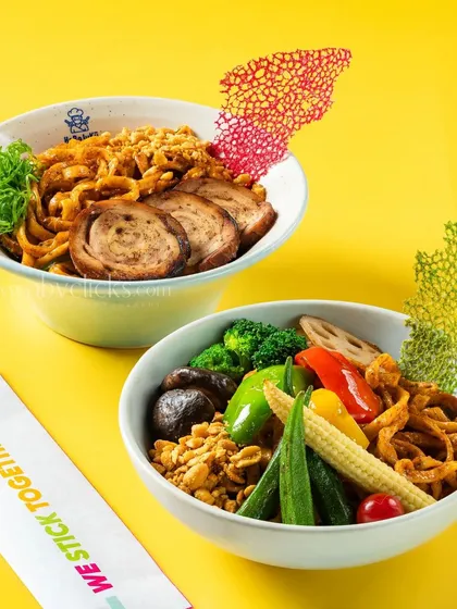 A pair of Japanese noodle bowls from Harajuku Tokyo Cafe against a bright yellow background.