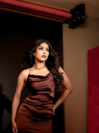 A studio shot that shows the model in a full-length pose against a simple background. The lighting is set up to highlight both the model and the red accent wall in the studio.