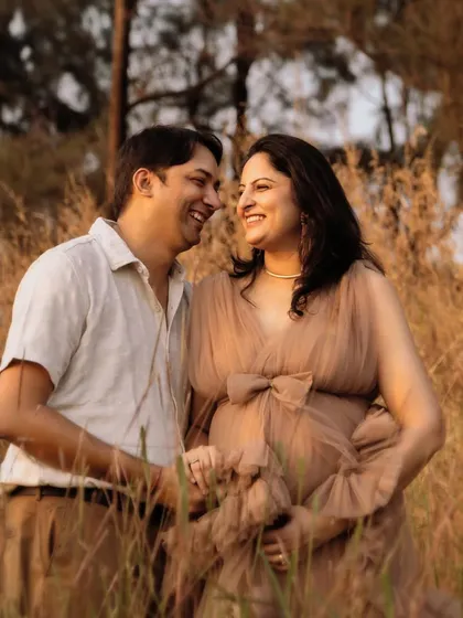 The best moments are often the ones in between poses. Here, a shared laugh during a maternity session in a beautiful sunlit field shows the happy anticipation and easy comfort this couple shares as they await their baby.