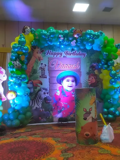 The main stage backdrop for the jungle party, featuring a balloon arch and a large personalized print.