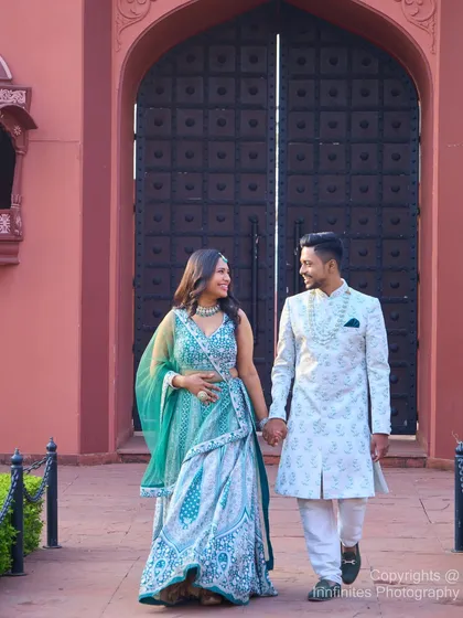 A candid moment captured as the couple walks hand-in-hand from the grand entrance of our pink palace set, dressed in beautifully coordinated traditional Indian attire.