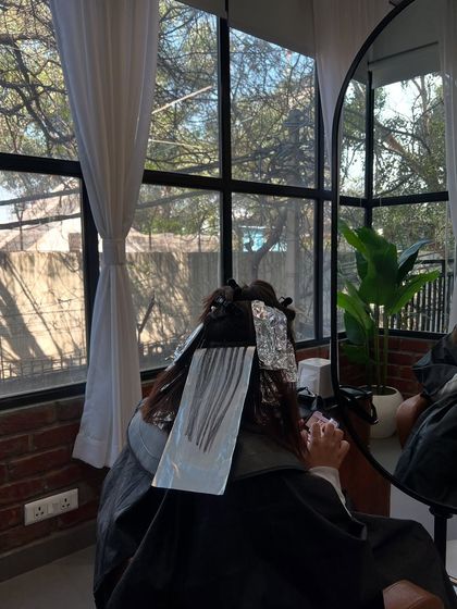 The coloring process in action. Here, a client is getting foils applied for a lived-in color service, relaxing by our large windows.