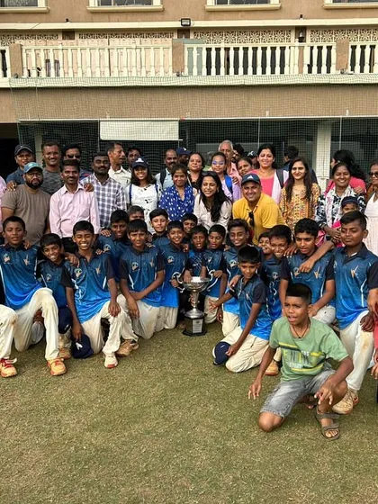 The entire support system of players, coaches, and parents celebrating the Bhaskar Trophy victory together.