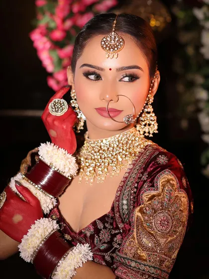 A beautiful close-up of a bride, highlighting the intricate details of her makeup and jewelry. The winged eyeliner and perfectly defined lips create a look that is both classic and modern.