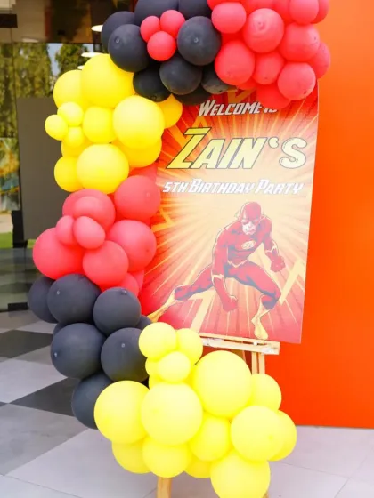 A close-up of the welcome sign for Zain's 5th birthday party, featuring The Flash. The red, yellow, and black balloons perfectly match the superhero theme.