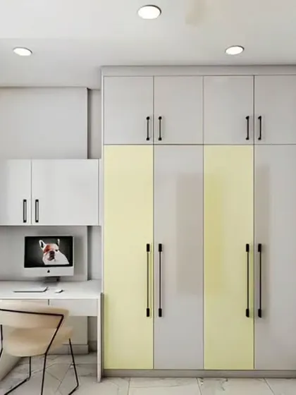 A space-efficient bedroom design that incorporates a compact study desk into the wardrobe unit. The grey and yellow color scheme adds a modern and youthful touch.