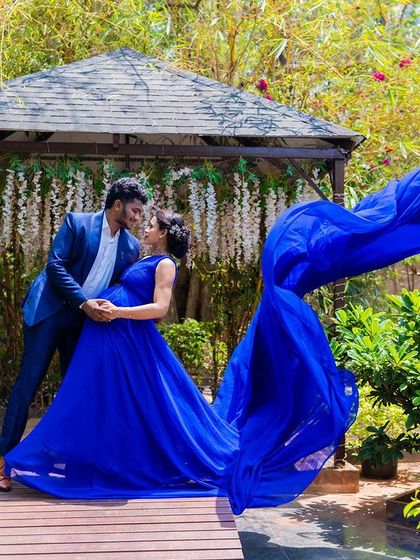 A romantic maternity moment on the wooden bridge with a flowing blue gown.